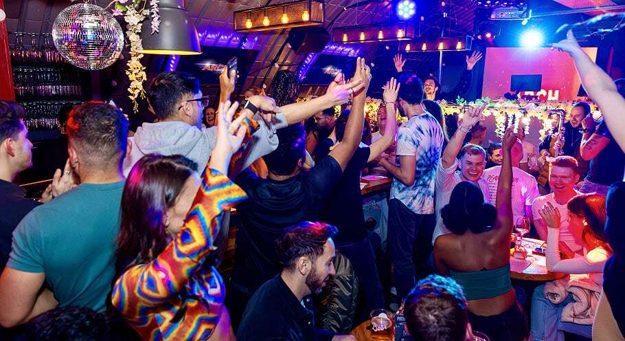 A lively crowd celebrates a special event at Arch Clapham, possibly the best gay bar in London.