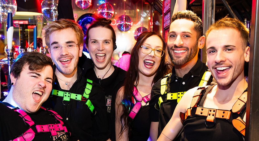 A party shot of the bar crew at Arch Clapham. They are smiling at the camera, enjoying a vibrant night at one of London's top LGBTQ+ night spots.